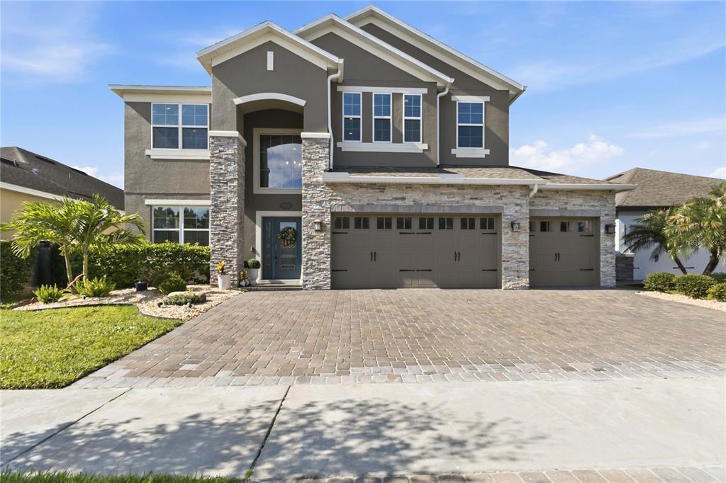 A two-story house with a stone facade, a three-car garage, and a paved driveway — 3438 PUXTON DRIVE, ORLANDO, FL