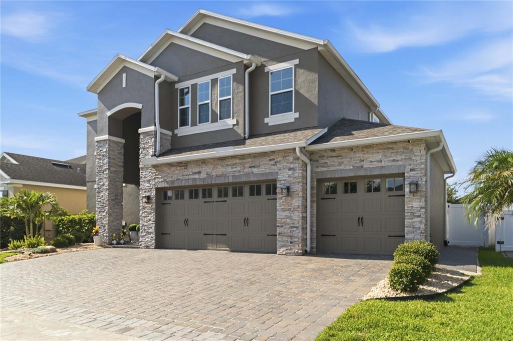 A two-story house with a stone facade, gray stucco, and a three-car garage — 3438 PUXTON DRIVE, ORLANDO, FL