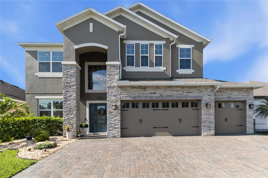 A two-story house with a stone facade, gray stucco, and a three-car garage — 3438 PUXTON DRIVE, ORLANDO, FL