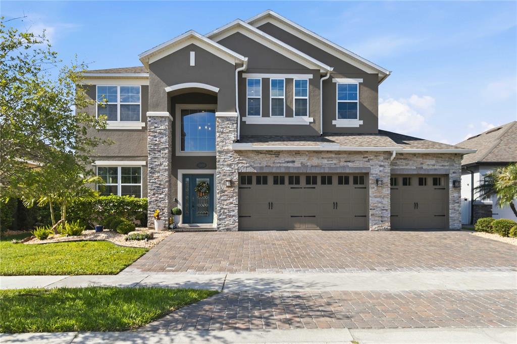 A two-story house with a stone facade, gray stucco, and a three-car garage — 3438 PUXTON DRIVE, ORLANDO, FL