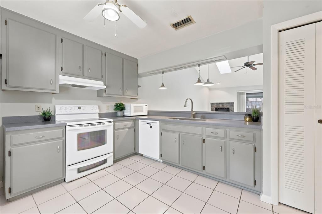 A kitchen with grey cabinets, white appliances, a tiled floor, and a pass-through window — 3711 NW 56TH LANE, GAINESVILLE, FL