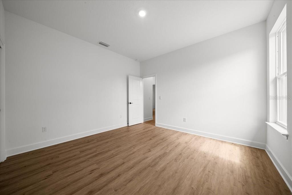 An empty bedroom features white walls, light wood-look flooring, and a single window — 11021 STILT AVENUE, WEEKI WACHEE, FL