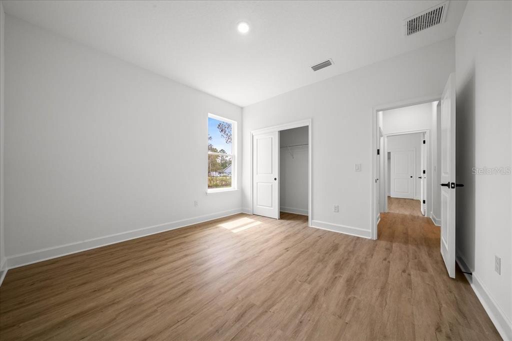 An empty bedroom with white walls, light wood-look flooring, a closet, and a doorway — 11021 STILT AVENUE, WEEKI WACHEE, FL