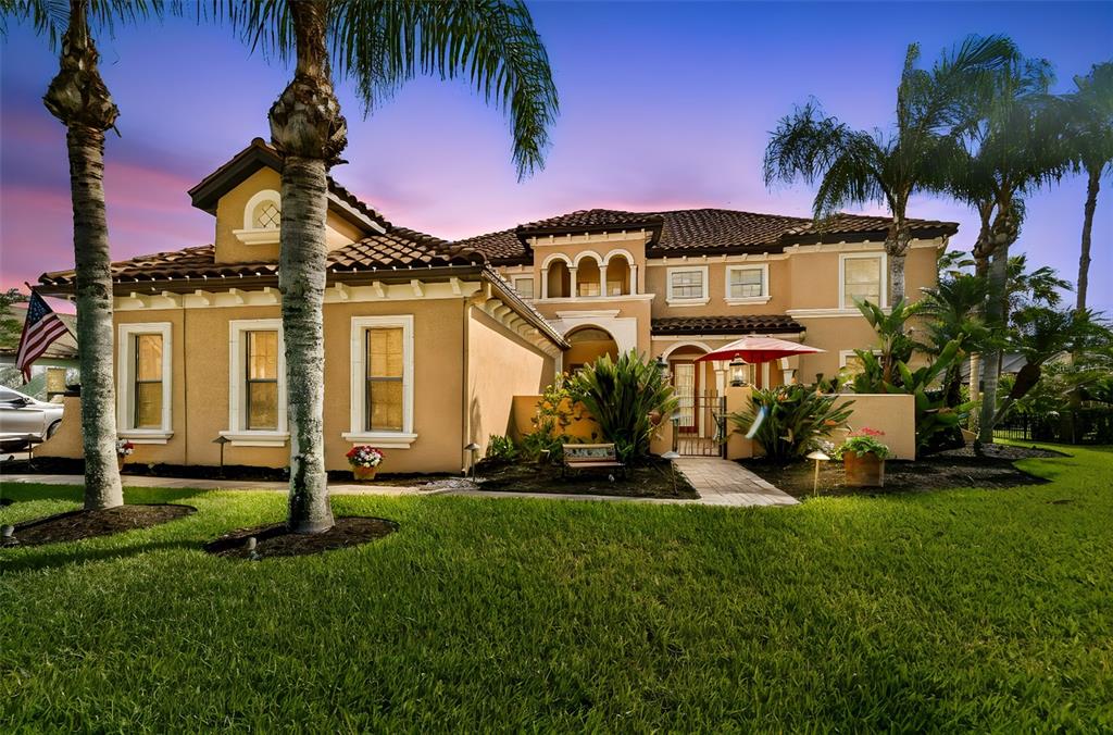 A two-story tan stucco house with a tile roof and palm trees in the yard — 3654 BALLASTONE DRIVE, LAND O LAKES, FL