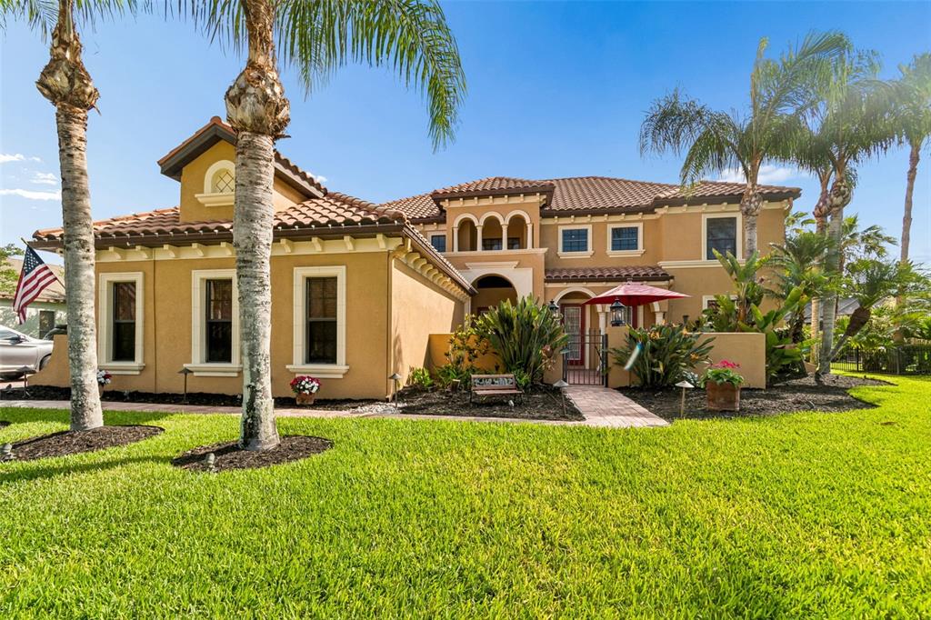 A two-story tan stucco house with a tile roof and palm trees in the yard — 3654 BALLASTONE DRIVE, LAND O LAKES, FL