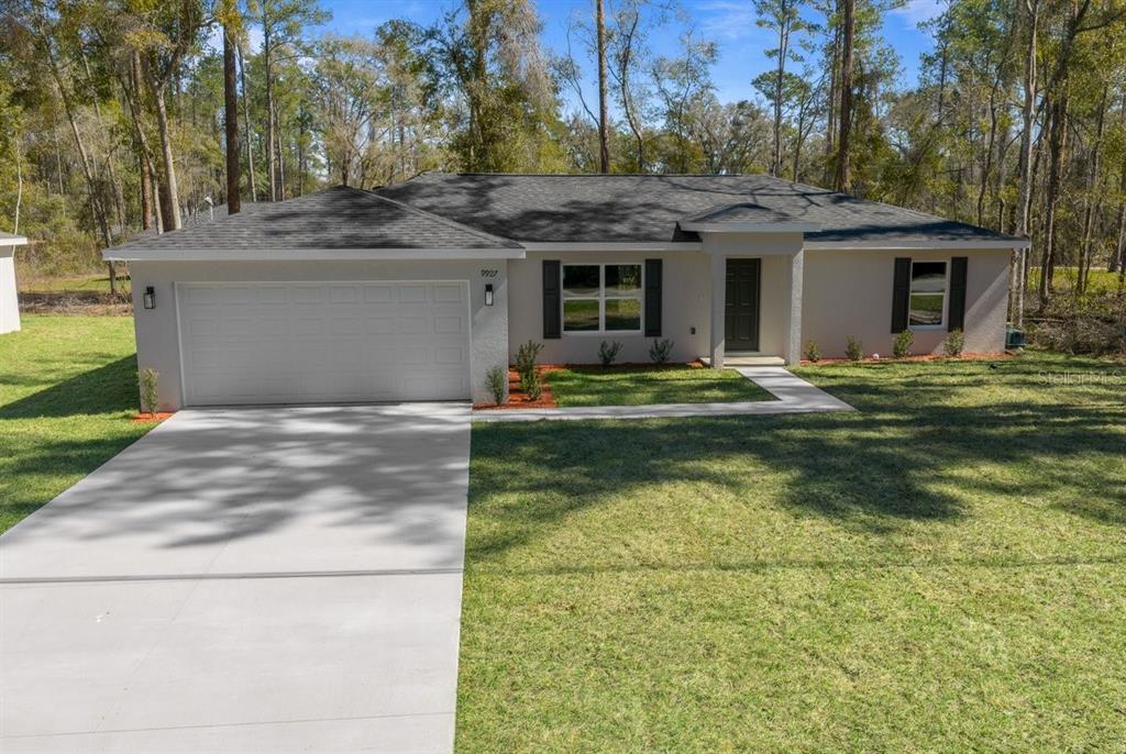 A single-story house with a white exterior, dark roof, and a two-car garage — 9927 N ATHENIA DRIVE, CITRUS SPRINGS, FL