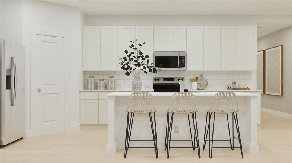 A modern kitchen features white cabinetry, a central island with three stools, and light flooring — 3018 GRANITE RIDGE AVENUE, MINNEOLA, FL