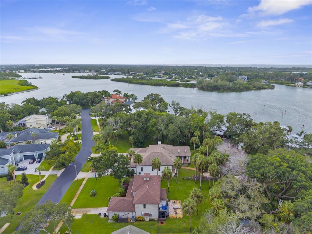 An aerial view shows a waterfront house with a long dock and multiple boats — 1705 MEYERS COVE DRIVE, TARPON SPRINGS, FL