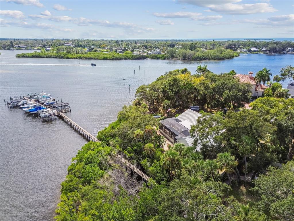 A white house with a blue front door and a circular driveway with brick accents — 1705 MEYERS COVE DRIVE, TARPON SPRINGS, FL