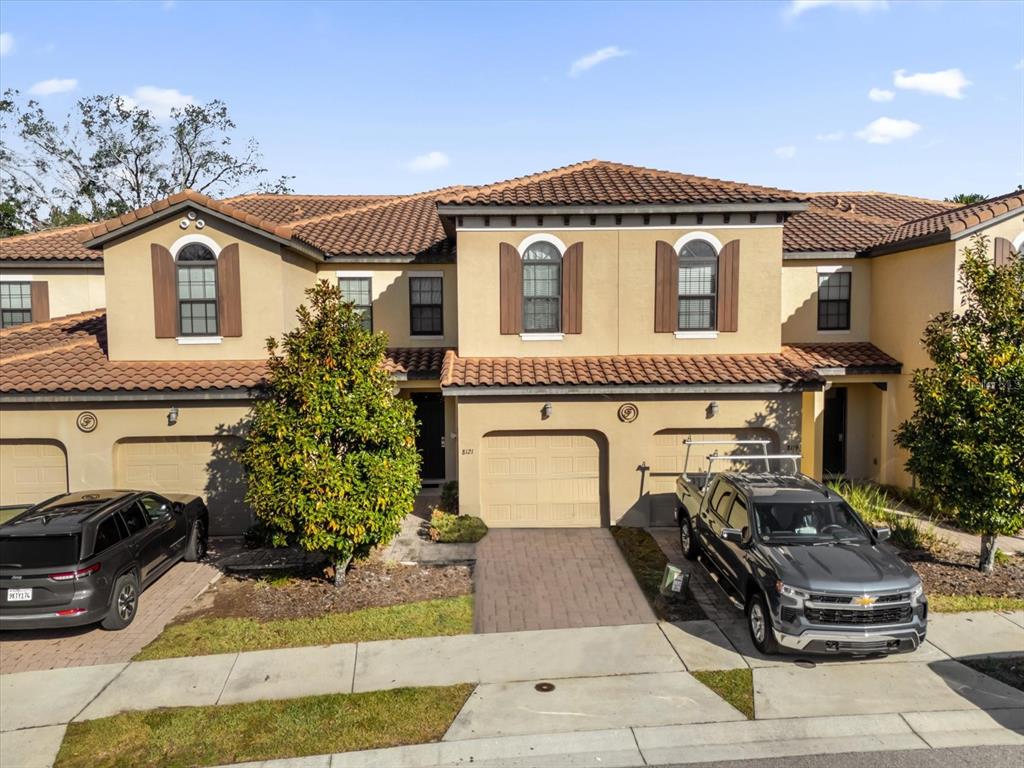 An exterior view of a multi-unit townhouse complex with tan stucco walls and tile roofs — 8121 ROSEVILLE BOULEVARD, DAVENPORT, FL