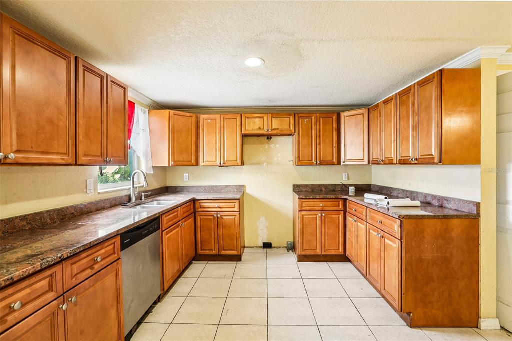 A kitchen with wood cabinets, granite countertops, tile flooring, and a missing stove area — 4128 BADEN DRIVE, HOLIDAY, FL