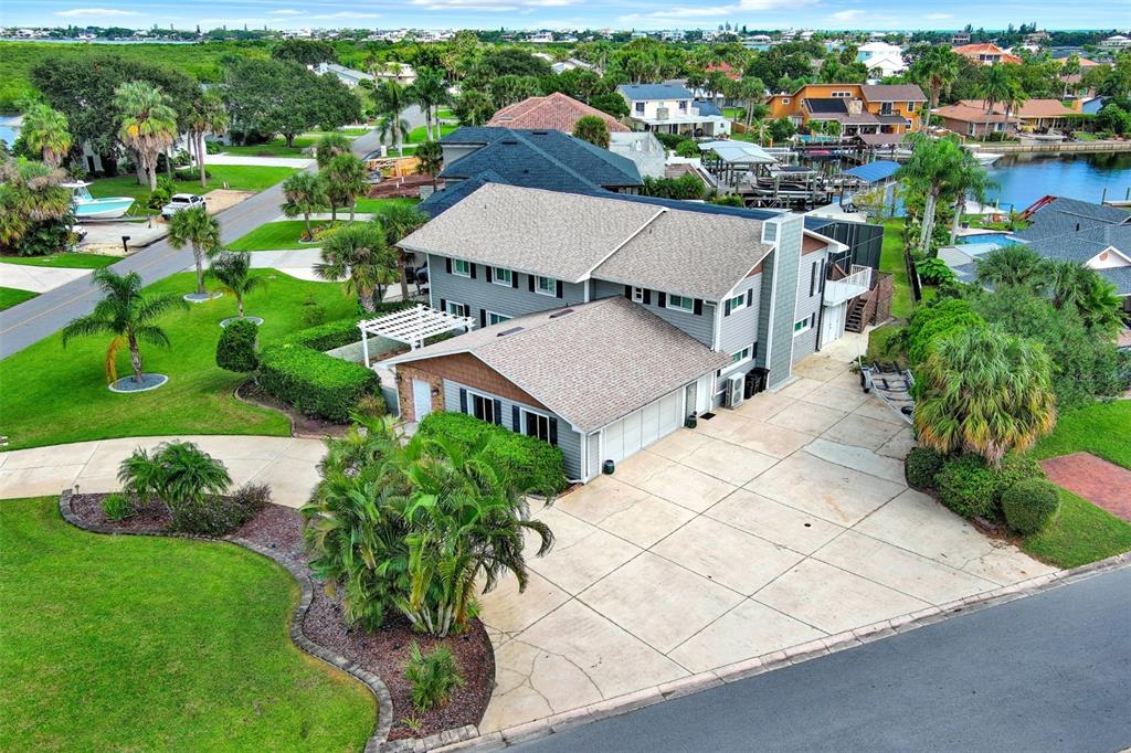 An aerial view of a two-story gray house with a large concrete driveway and landscaping — 301 QUAY ASSISI, NEW SMYRNA BEACH, FL