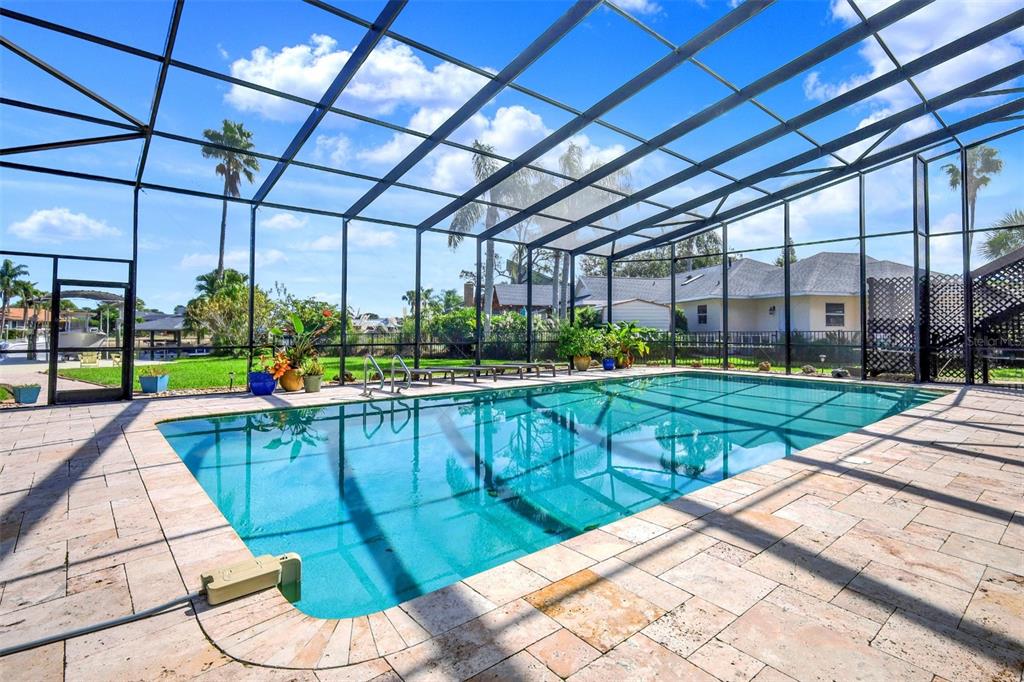 A screened-in swimming pool with stone pavers and a view of a grassy backyard — 301 QUAY ASSISI, NEW SMYRNA BEACH, FL