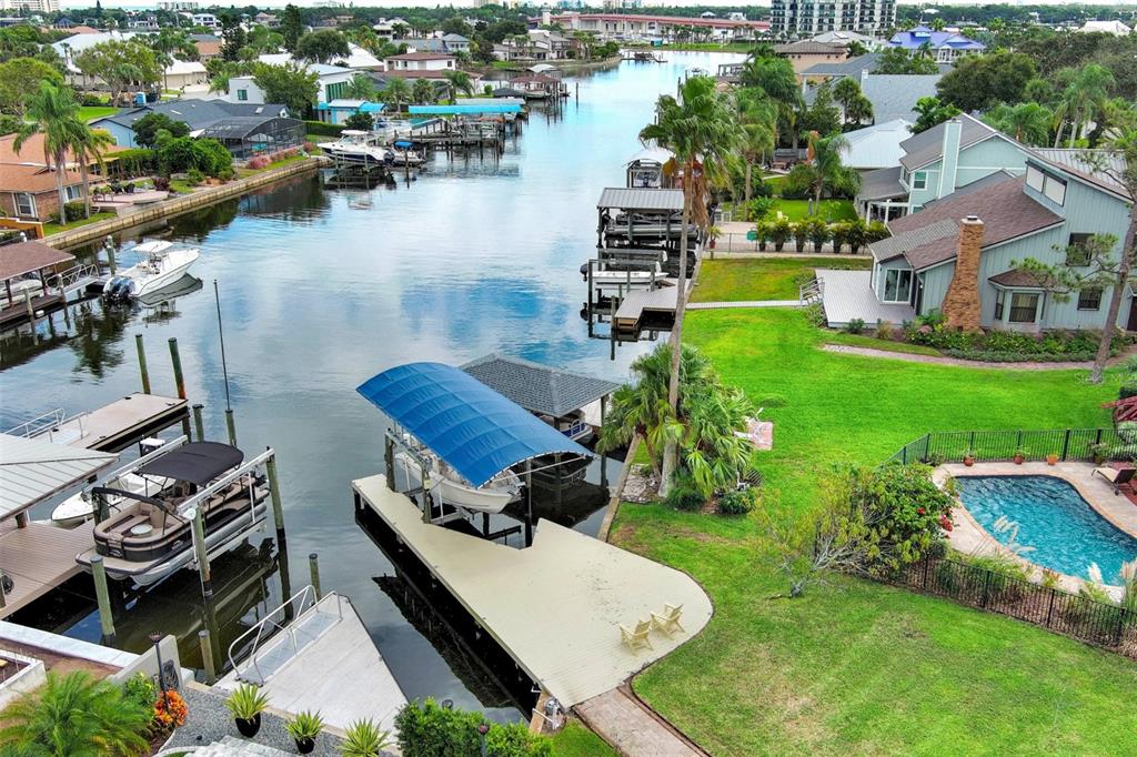 An aerial view shows a canal-side home with a private pool, boat dock, and lift — 301 QUAY ASSISI, NEW SMYRNA BEACH, FL