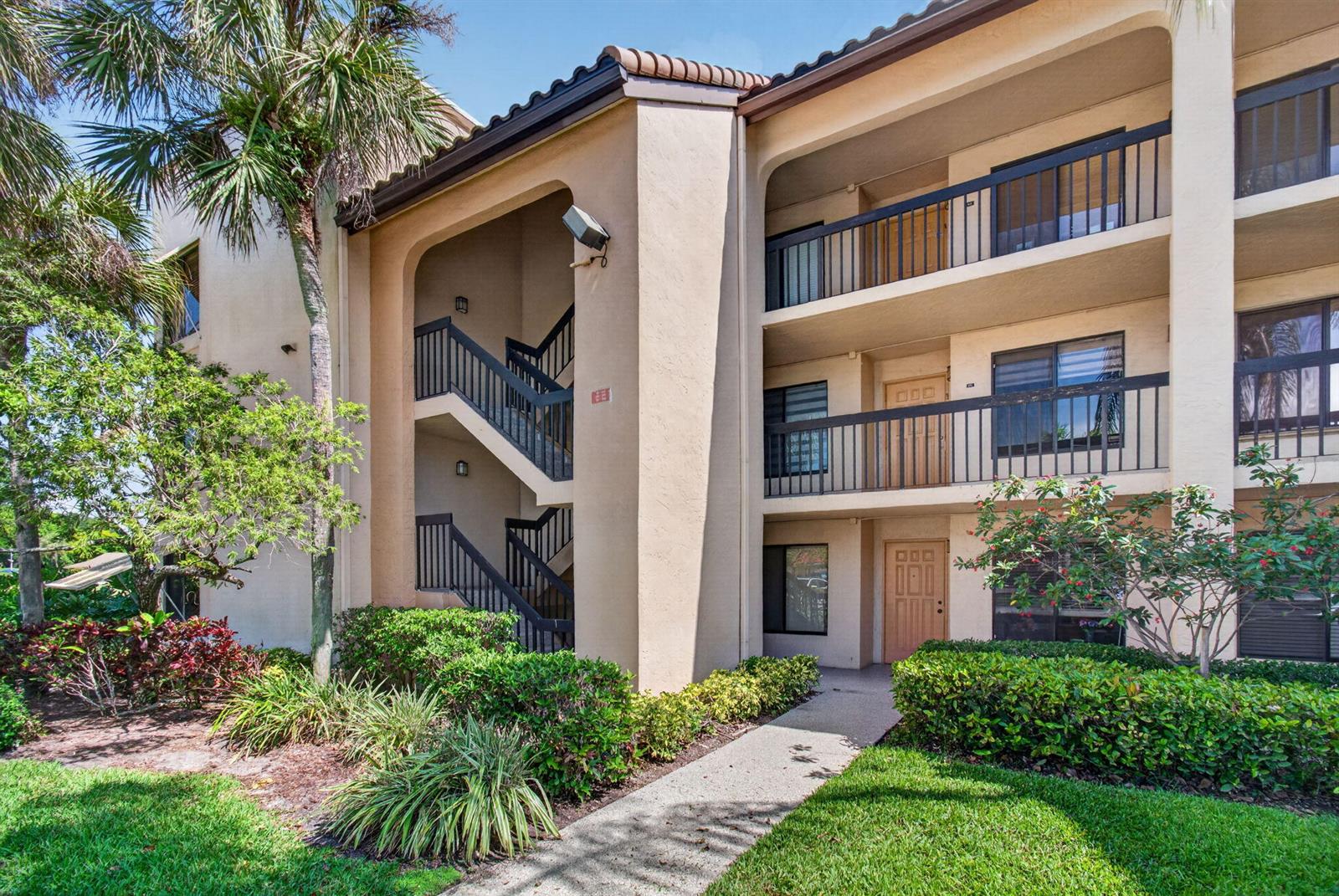 A three-story apartment building features exterior staircases, balconies, and a concrete walkway through landscaping — 10174 Mangrove Drive # 201, Boynton Beach FL 33437, BOYNTON BEACH, FL