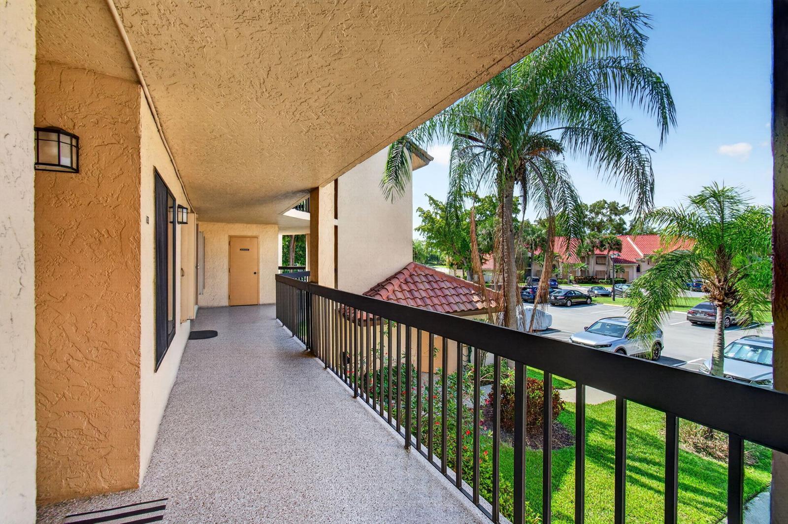 An outdoor balcony with a textured ceiling, metal railing, and a view of a parking lot — 10174 Mangrove Drive # 201, Boynton Beach FL 33437, BOYNTON BEACH, FL