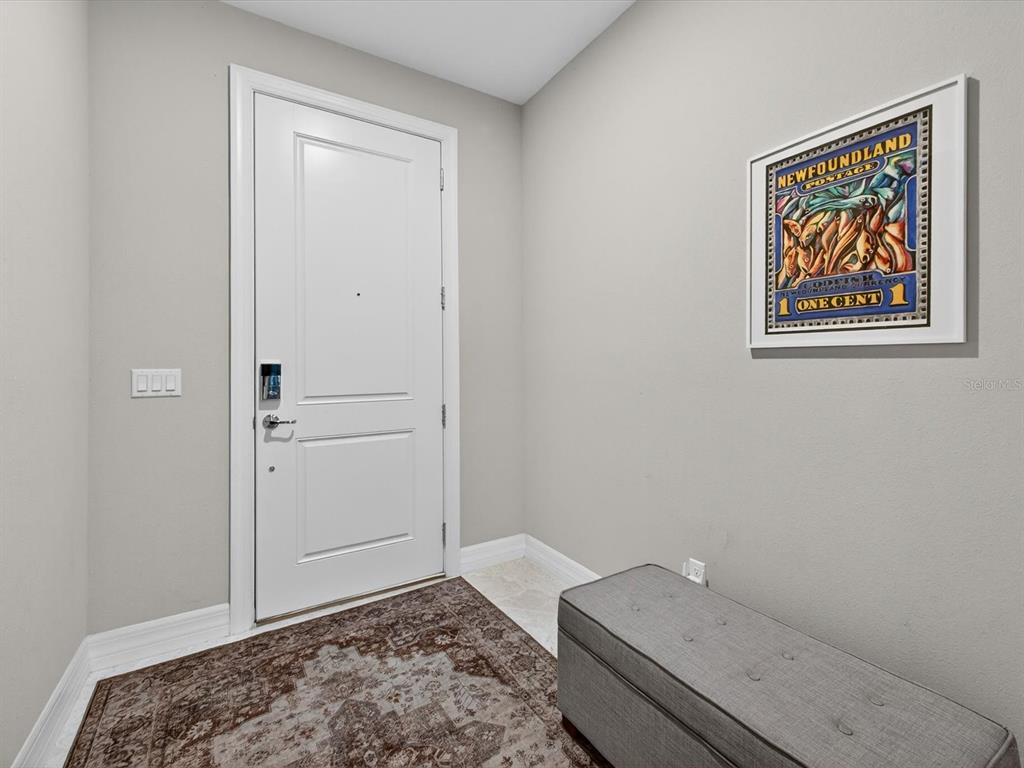 An entryway features a white door, a gray storage bench, and a framed postage print — 11708 MEADOW GROVE CIRCLE, ORLANDO, FL