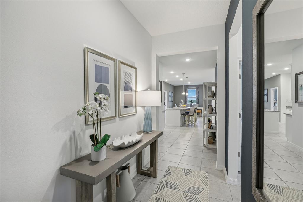 A hallway with a console table, artwork, and a view into an open-concept kitchen — 23599 GRINDSTONE WAY, SORRENTO, FL