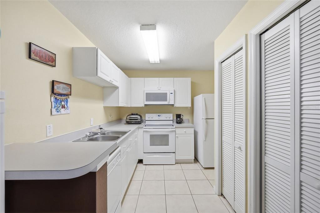 A kitchen features white cabinets, white appliances, a double sink, and light-colored tile flooring — 2788 CLUB CORTILE CIRCLE UNIT A, KISSIMMEE, FL
