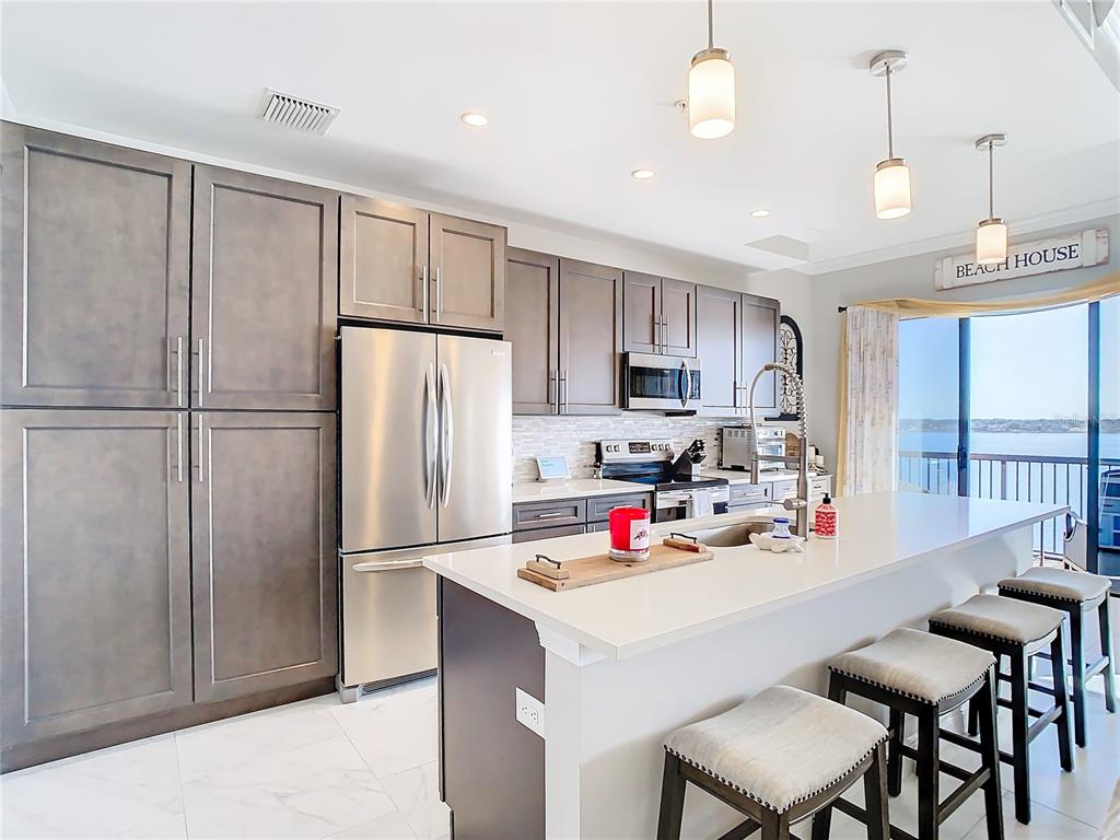 A modern kitchen features dark cabinetry, stainless steel appliances, a white island, and water views — 16300 COUNTY ROAD 455 UNIT 610, MONTVERDE, FL