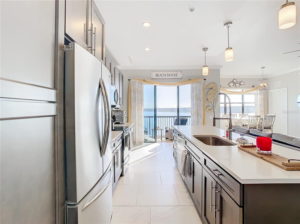 A modern kitchen features dark cabinetry, white countertops, stainless steel appliances, and a balcony view — 16300 COUNTY ROAD 455 UNIT 610, MONTVERDE, FL