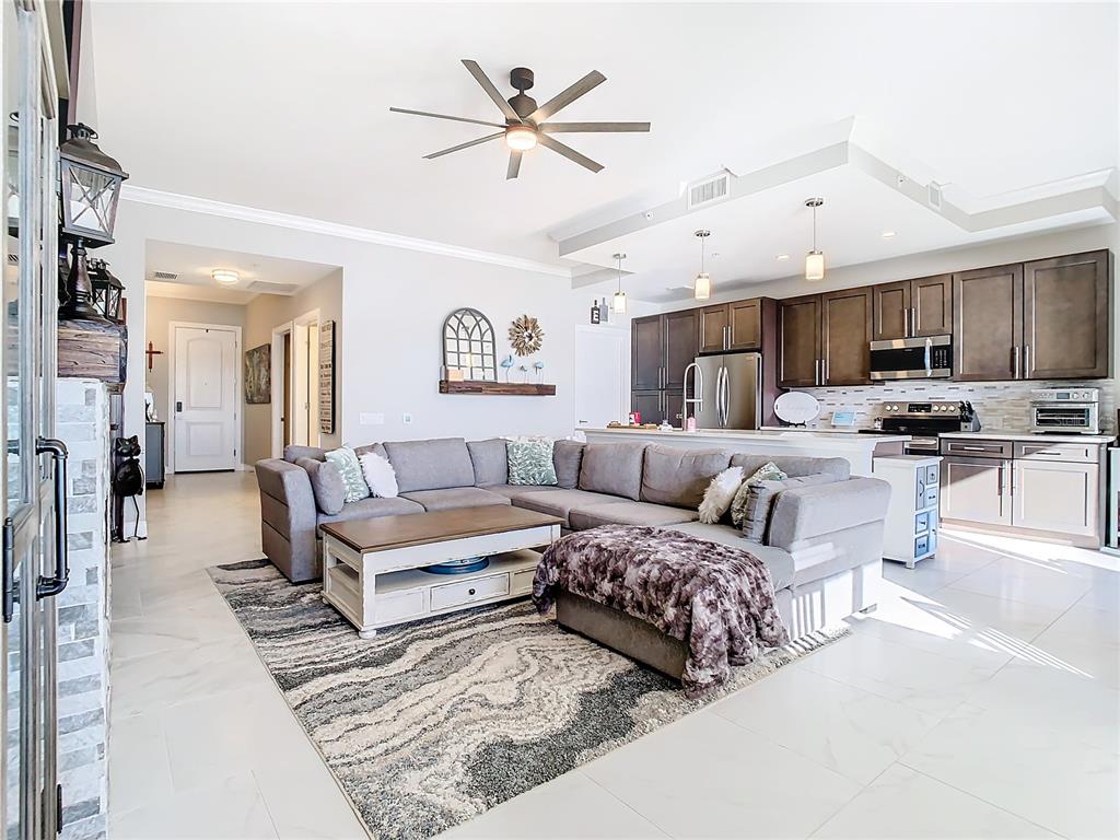 A living room with a gray sectional sofa, coffee table, and an open-concept kitchen — 16300 COUNTY ROAD 455 UNIT 610, MONTVERDE, FL