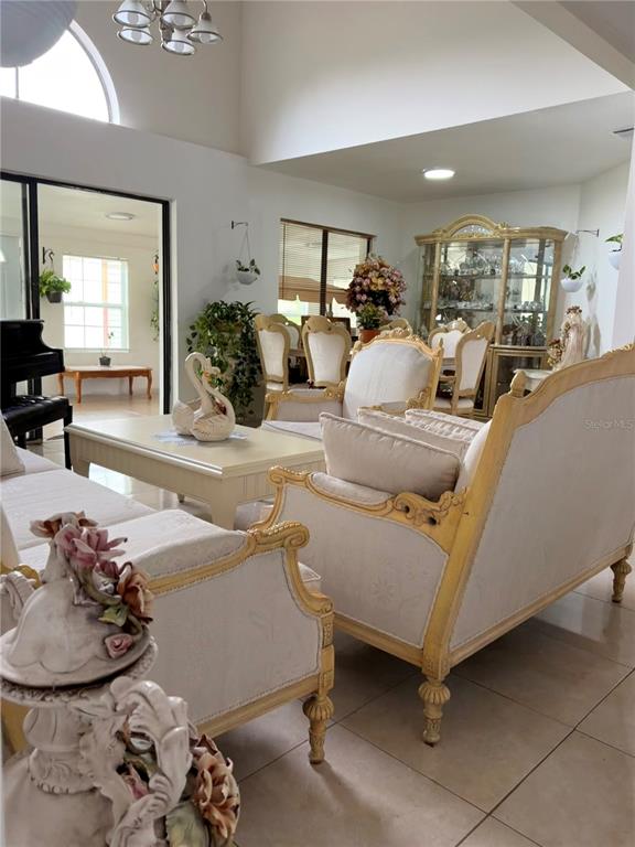 A living room features a grand piano, ornate furniture, and a sliding door to a sunroom — 499 CHICAGO WOODS CIRCLE, ORLANDO, FL