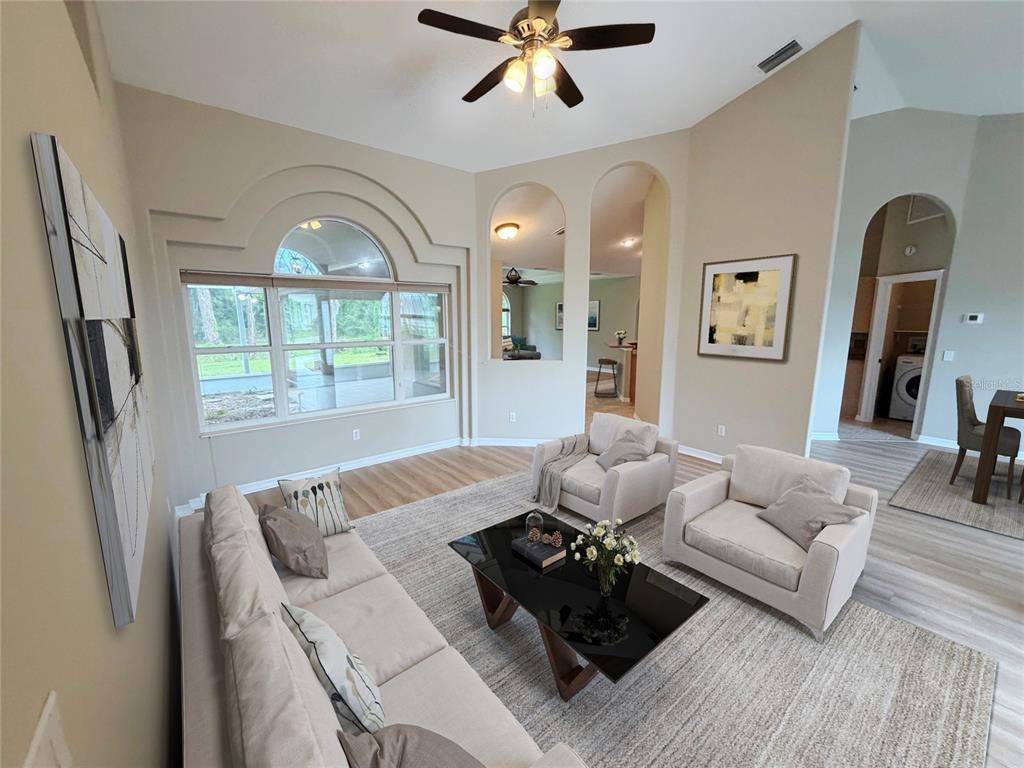 A living room with a vaulted ceiling, arched wall cutouts, and a large window — 10 ELLIOT PLACE, PALM COAST, FL