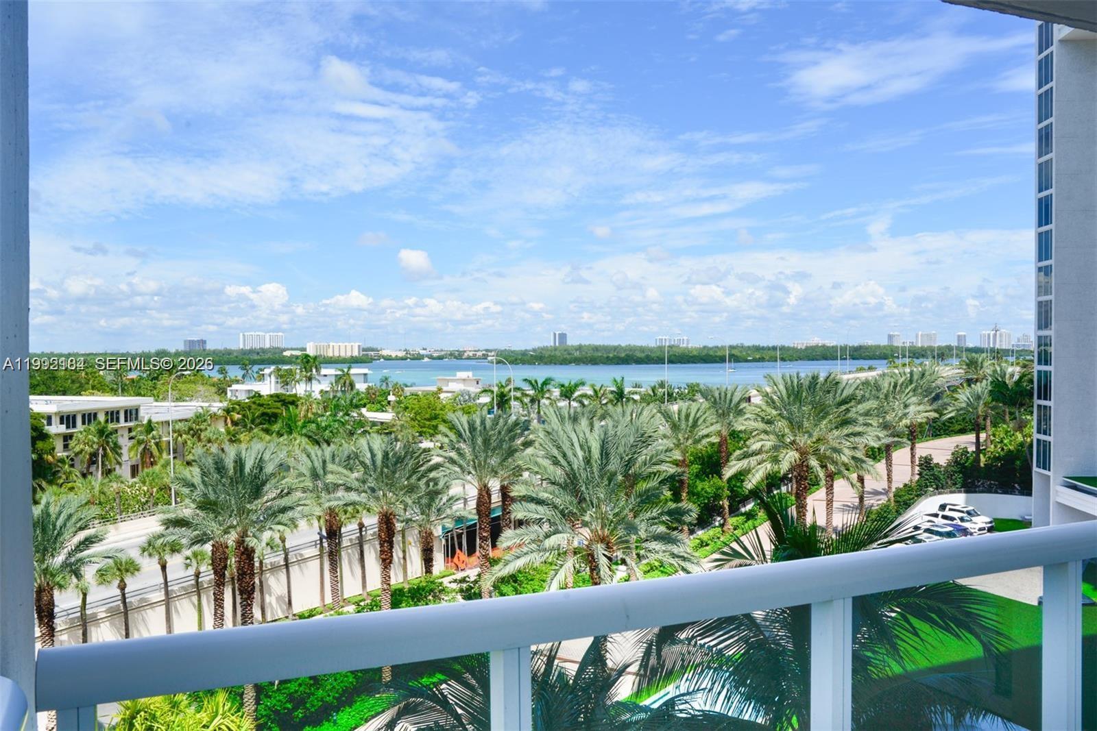 A balcony view overlooks palm trees, a road, and a body of water under a sky — 10275 Collins Ave # 523, Bal Harbour FL 33154, BAL HARBOUR, FL