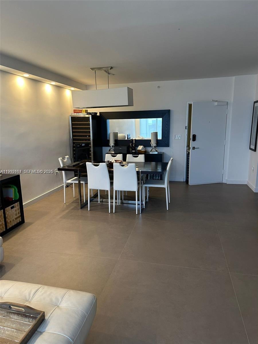 A dining area features a dark table, white chairs, a wine cooler, and tile flooring — 10275 Collins Ave # 523, Bal Harbour FL 33154, BAL HARBOUR, FL