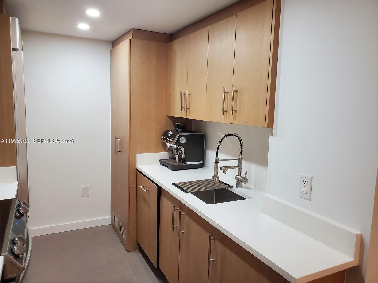 A kitchenette features light wood cabinets, white countertops, a sink, and a coffee machine — 10275 Collins Ave # 523, Bal Harbour FL 33154, BAL HARBOUR, FL