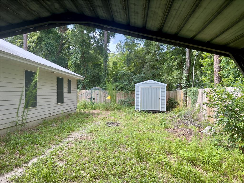 A backyard view showing a house exterior, a storage shed, and a wooden fence — 930 NE 14TH AVENUE, TRENTON, FL