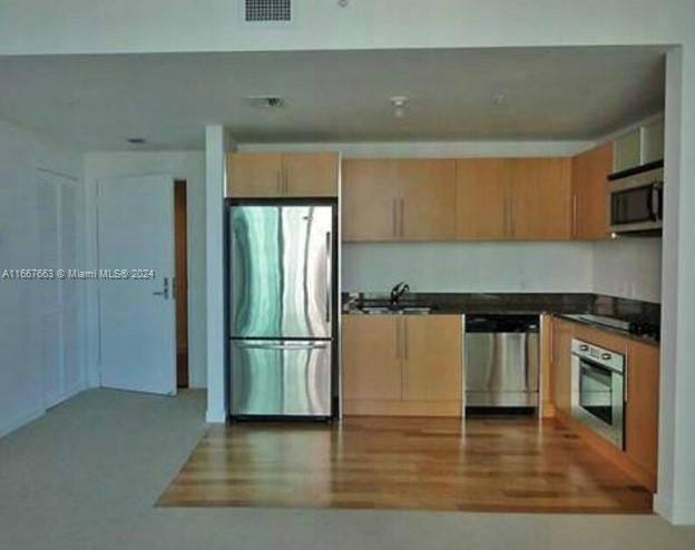 A kitchen with light wood cabinets, stainless steel appliances, and hardwood flooring — 300 S Biscayne Blvd # 1703, Miami FL 33131, MIAMI, FL