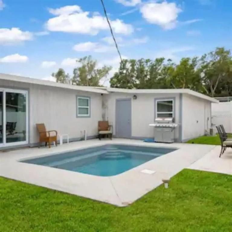 A backyard features a rectangular swimming pool, a concrete patio, and a single-story house exterior — 2539 TRINIDAD STREET, SARASOTA, FL