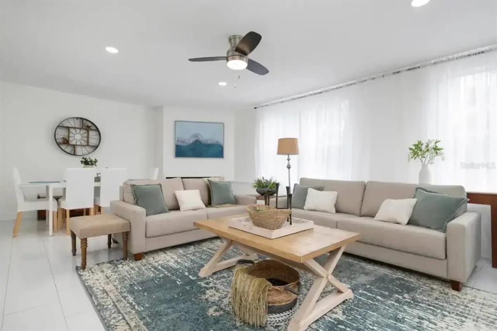 A living room features two beige sofas, a wooden coffee table, and a blue rug — 2539 TRINIDAD STREET, SARASOTA, FL