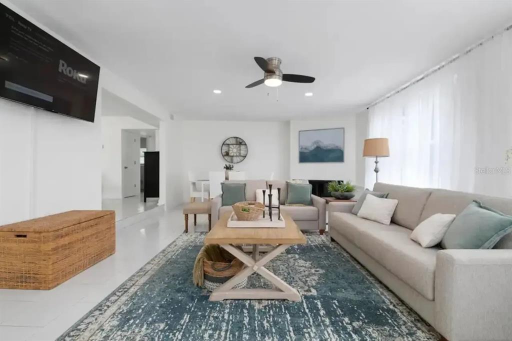 A bright living room features a large blue area rug, two sofas, and a television — 2539 TRINIDAD STREET, SARASOTA, FL