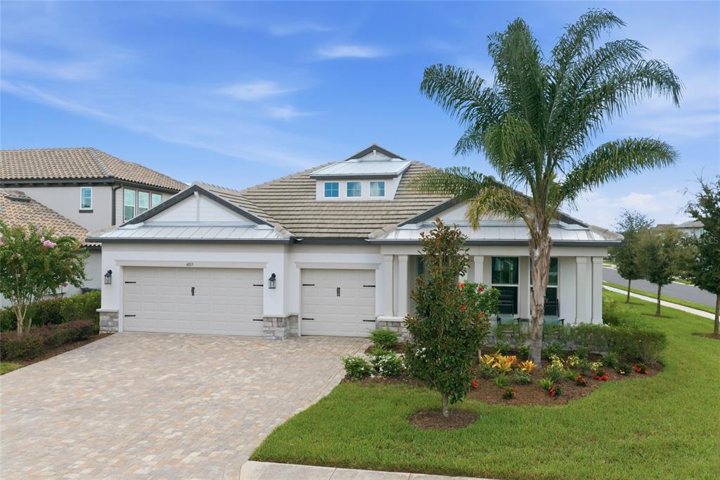 A single-story house with a three-car garage, a tiled roof, and a palm tree out front — 4815 HONEY DEW LANE, BRADENTON, FL