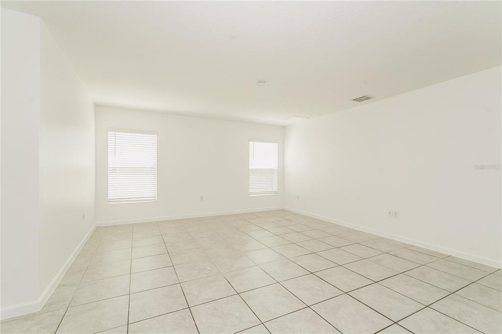 An empty room with white walls, two windows with blinds, and light-colored tiled flooring — 1473 LUCERNE LOOP ROAD NE, WINTER HAVEN, FL