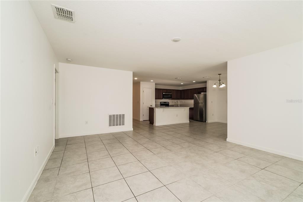 An open-concept living area with light tile flooring leads to a kitchen with dark cabinets — 1473 LUCERNE LOOP ROAD NE, WINTER HAVEN, FL
