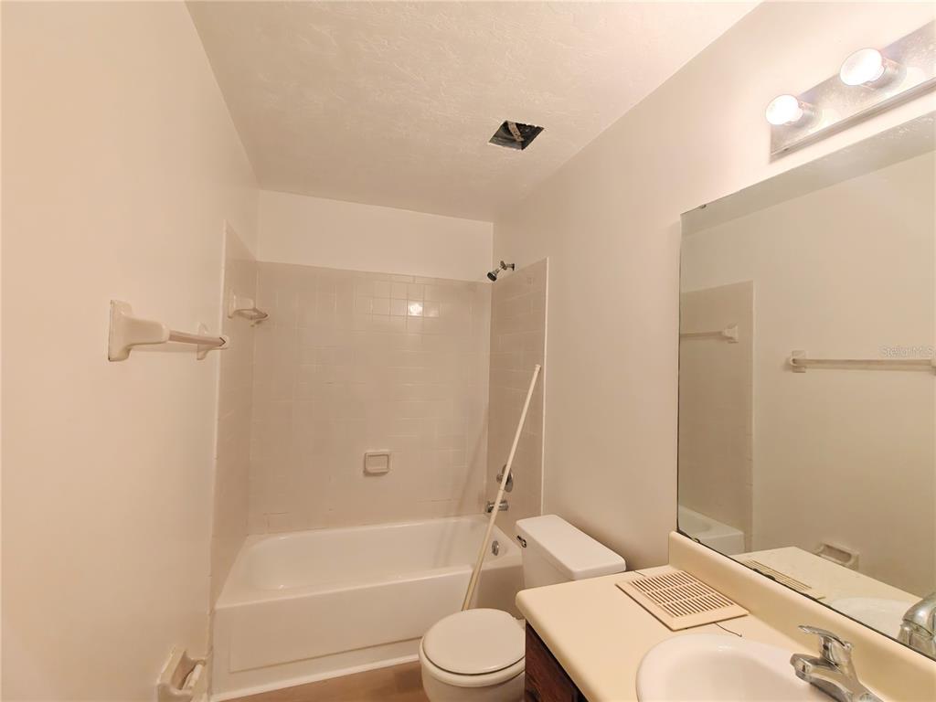 A bathroom features a tub-shower combination, a toilet, and a vanity with a mirror — 6133 NW 33RD STREET, GAINESVILLE, FL