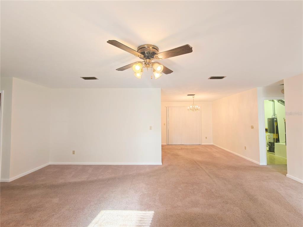 A carpeted living room features a ceiling fan, recessed lighting, and a view into another area — 6133 NW 33RD STREET, GAINESVILLE, FL