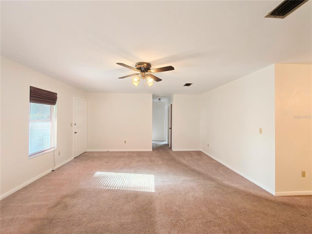 An empty room with beige carpet, white walls, a ceiling fan, and a window — 6133 NW 33RD STREET, GAINESVILLE, FL