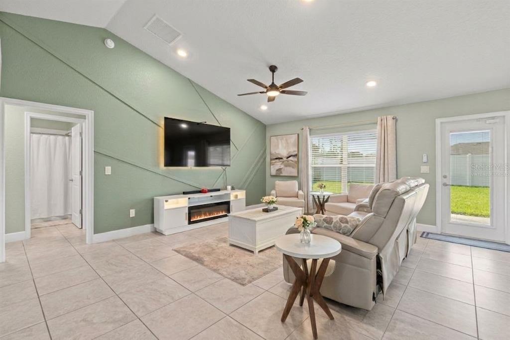 A living room features a green accent wall with geometric trim, tile flooring, and furniture — 9696 SE 157TH PLACE, SUMMERFIELD, FL
