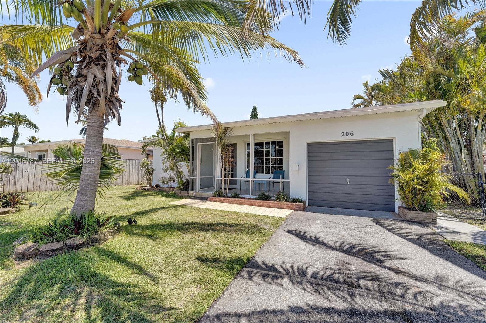 A single-story house with a grey garage door, a screened porch, and a palm tree — 206 SE 3rd St, Dania Beach FL 33004, DANIA BEACH, FL