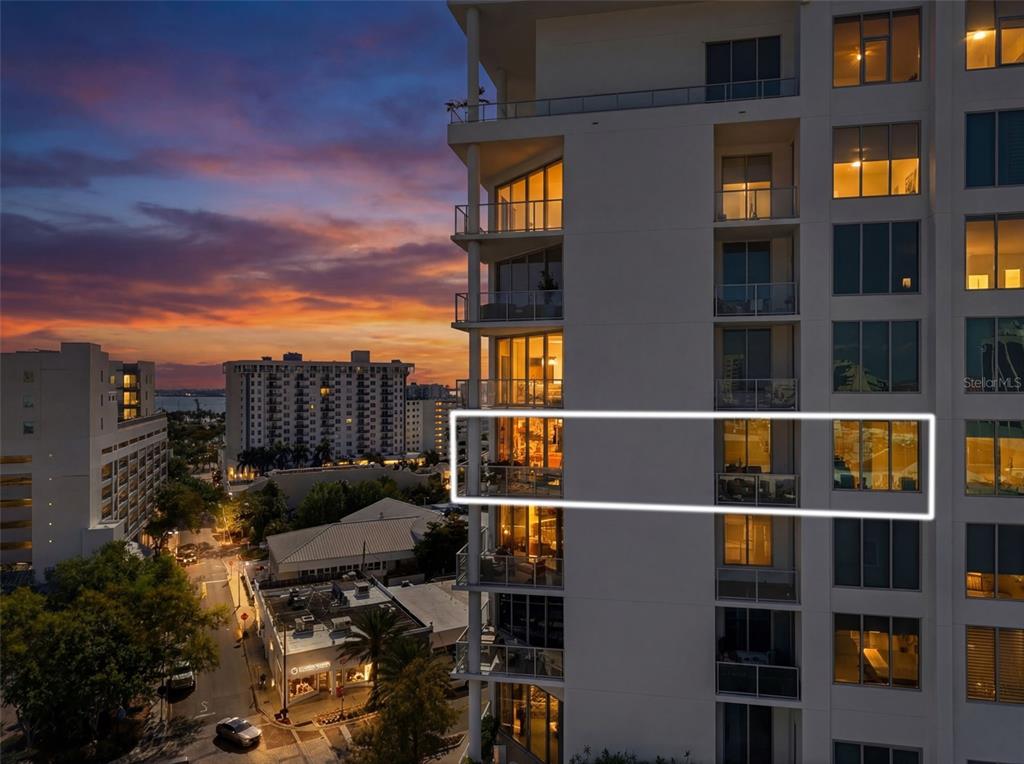 An aerial view of a coastal city skyline at sunset with a bridge over water — 111 S PINEAPPLE AVENUE UNIT 806, SARASOTA, FL