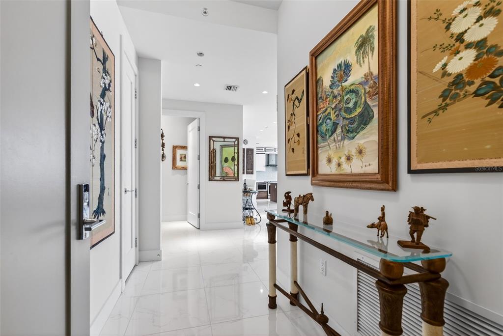 A modern dining and kitchen area with white tile floors, glass-topped table, and floor-to-ceiling windows — 111 S PINEAPPLE AVENUE UNIT 806, SARASOTA, FL