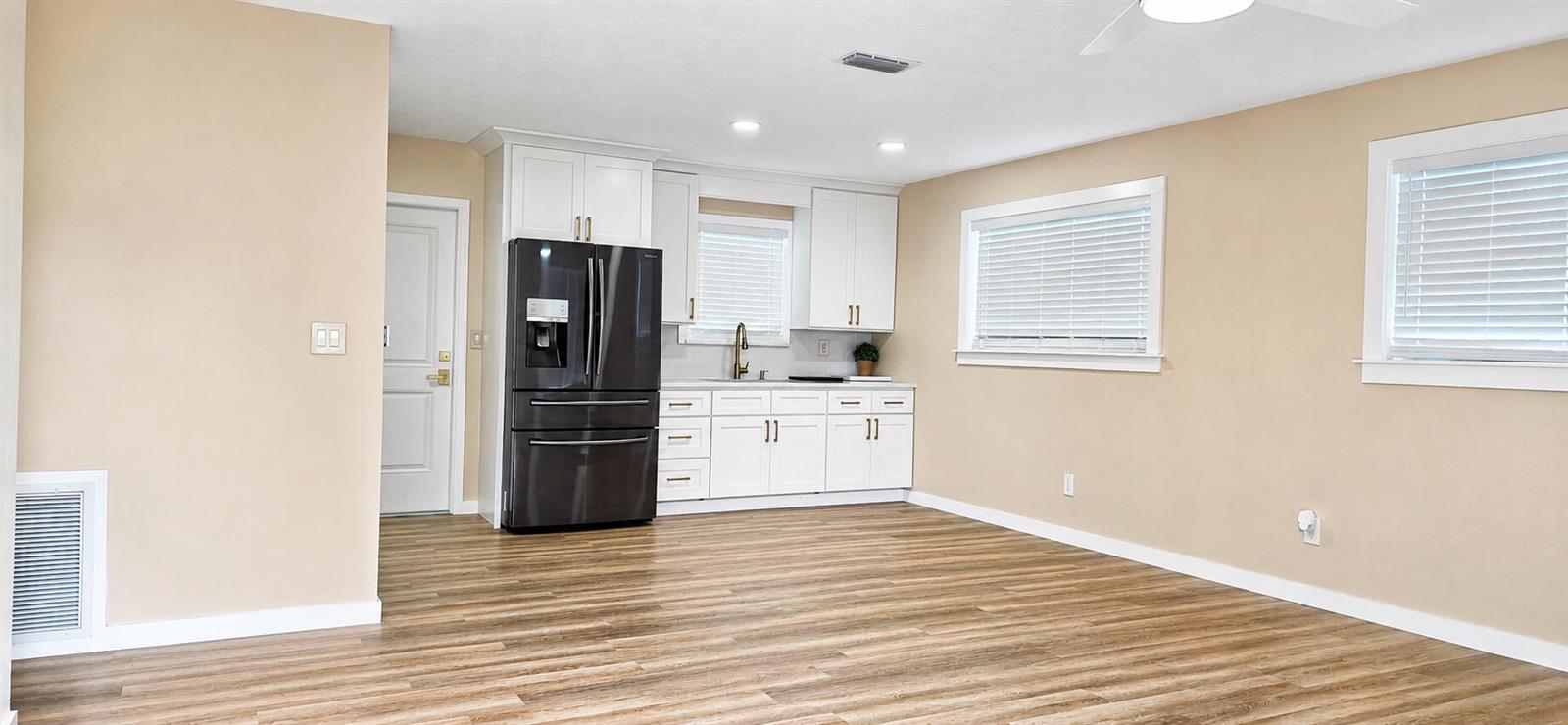 A kitchen with white cabinets, a black refrigerator, and wood-look flooring in an open room — 3095 NW 36th Street, Okeechobee FL 34972, OKEECHOBEE, FL