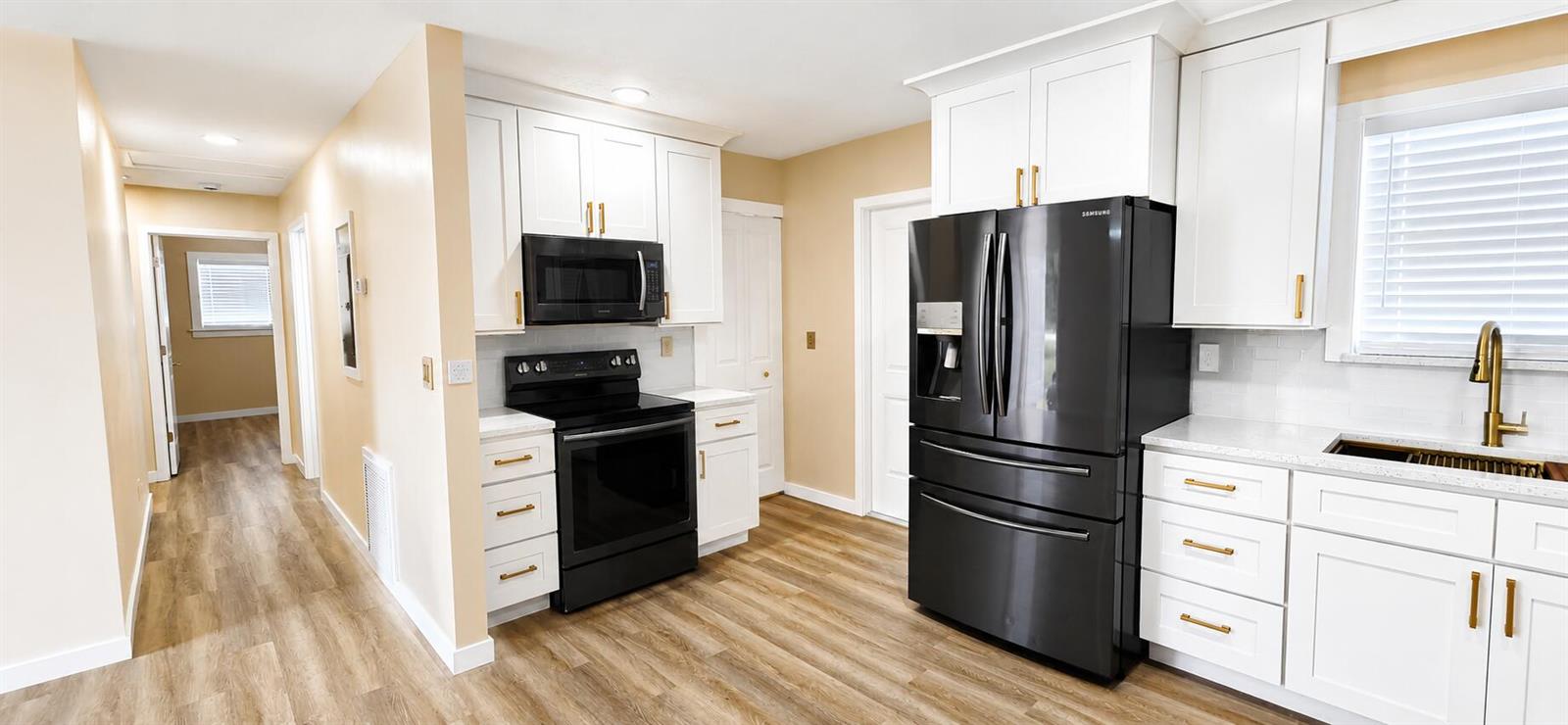A kitchen features white cabinets, black appliances, gold hardware, and light wood-look flooring — 3095 NW 36th Street, Okeechobee FL 34972, OKEECHOBEE, FL