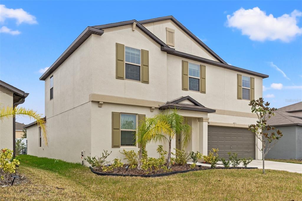 A two-story beige house with a two-car garage and green shutters under a blue sky — 194 ARGYLL DRIVE, SPRING HILL, FL