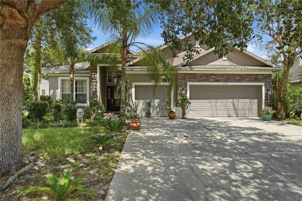 A single-story house with a stone facade, a three-car garage, and a palm tree — 458 WOODFORD DRIVE, DEBARY, FL